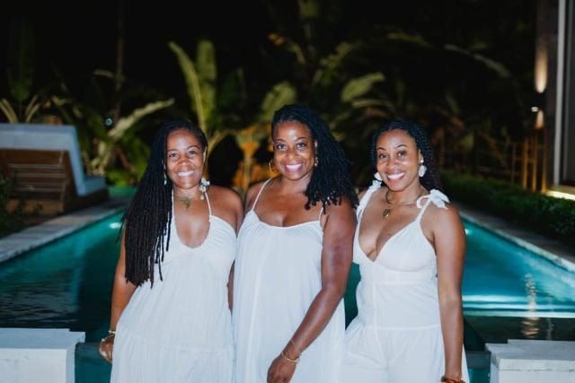 Three women in white at an evening pool ceremony