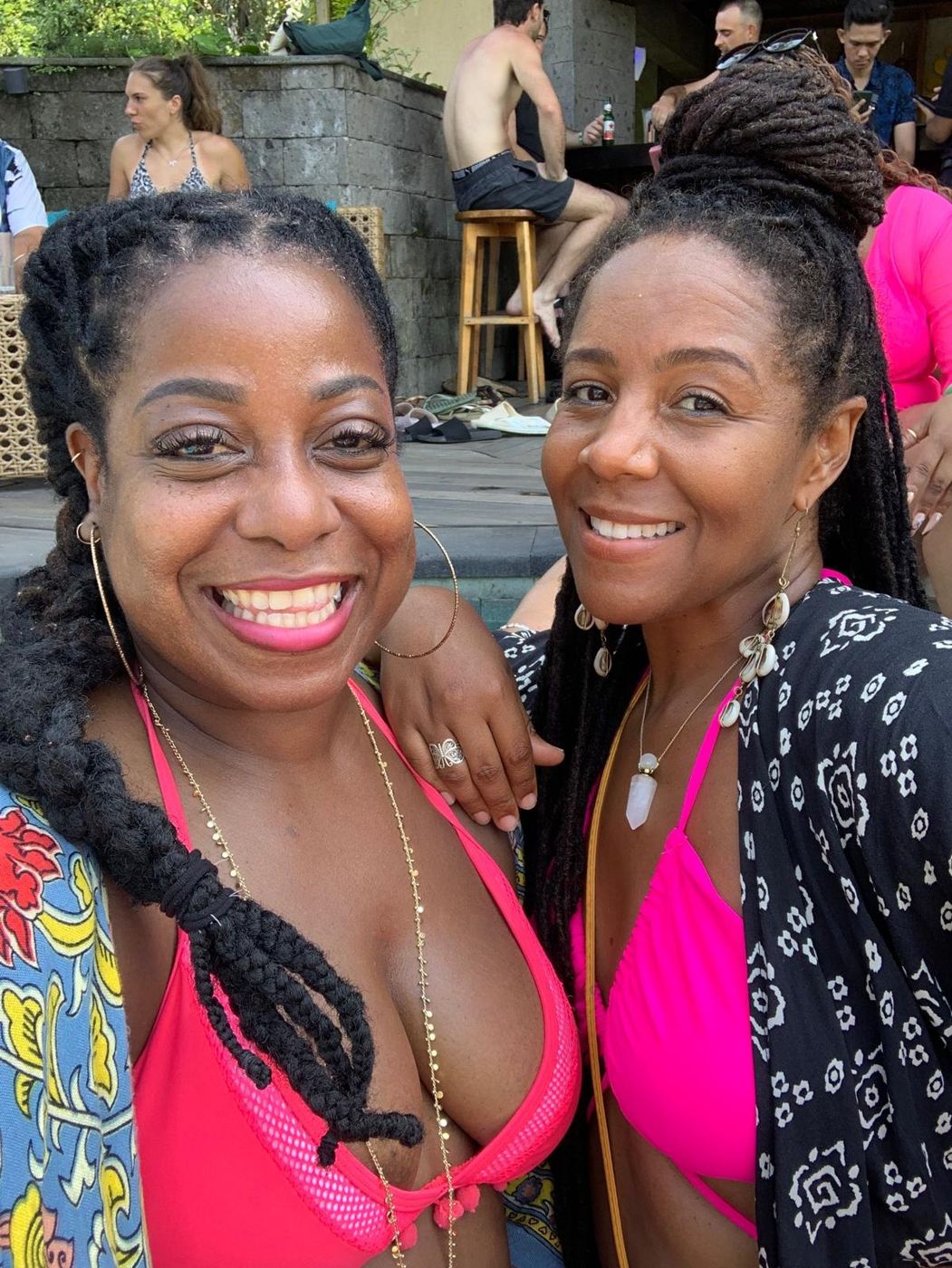 Two women smiling together at a poolside retreat gathering