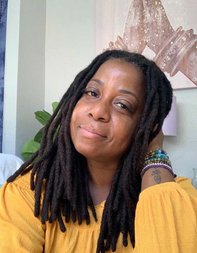 Terry, founder of The Healing Temple, smiling with her hand resting by her face